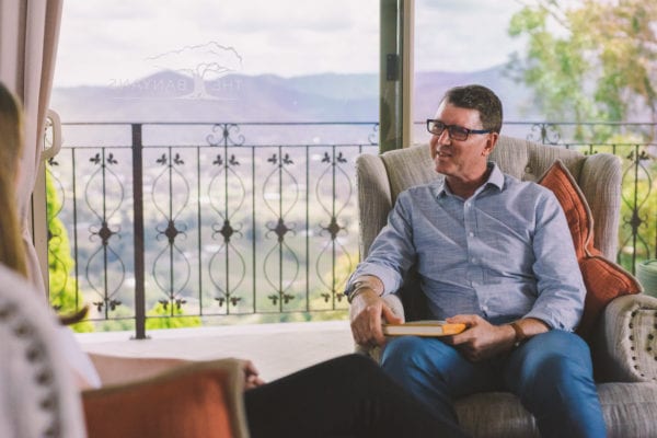 Male therapist talking to woman on chair at best drug rehab