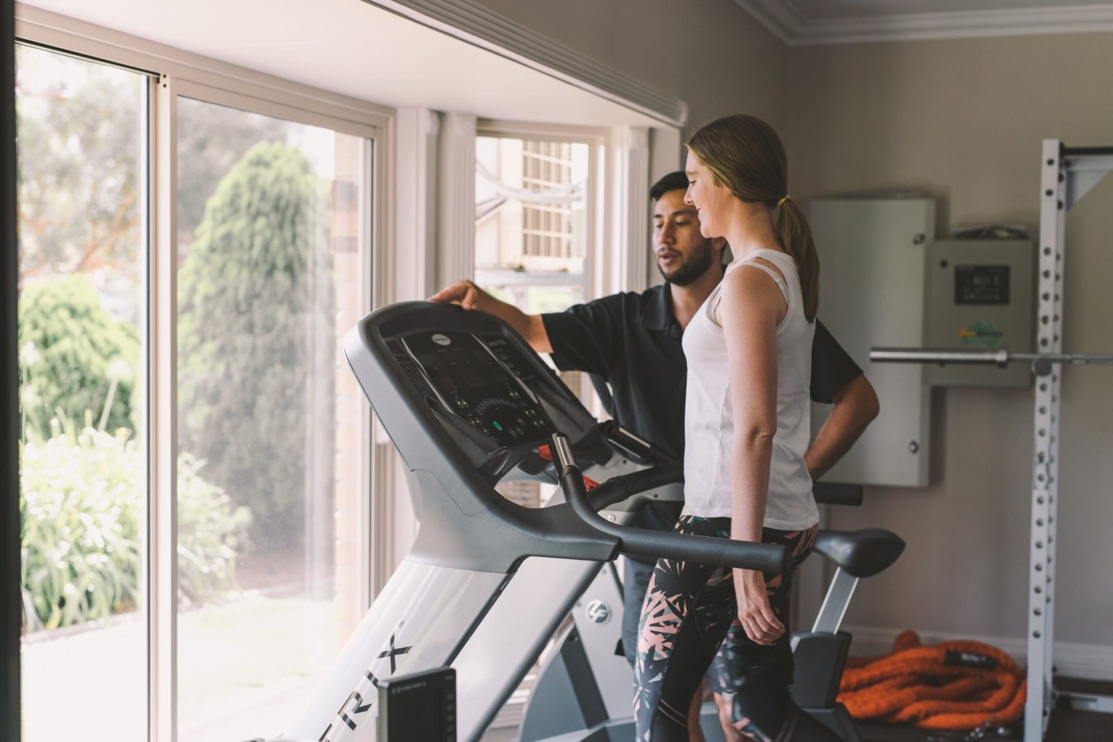 male trainer helping woman on tredmill