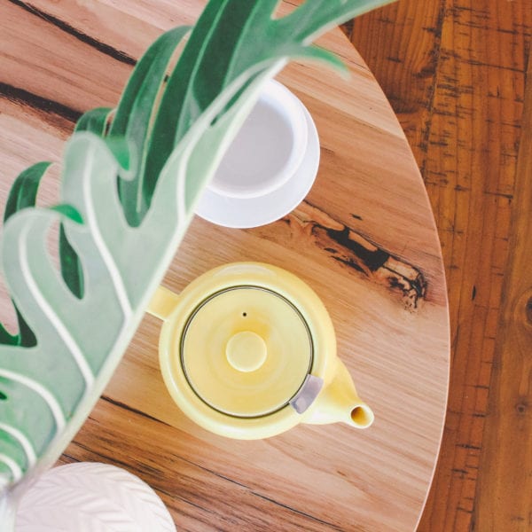 yellow teapot on table near plant