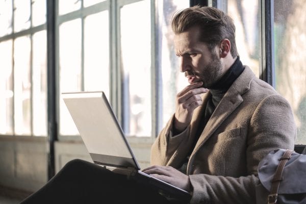 Man looks at computer with contemplative expresion