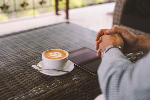 A man with a cup of coffee and his tablet
