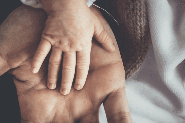 A baby's hand on an adult's palm