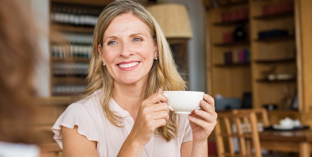 A blonde woman in a cafe enjoying a cup of coffee during dry july