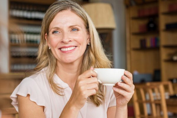 A blonde woman in a cafe enjoying a cup of coffee during dry july
