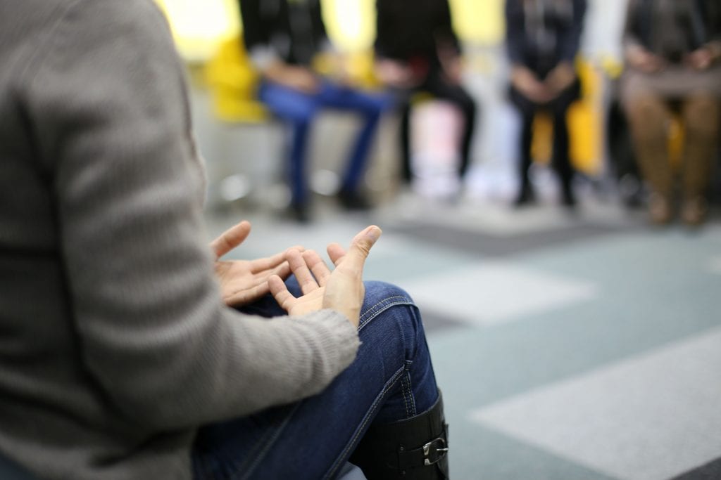 A person sharing at group therapy in a budget rehab