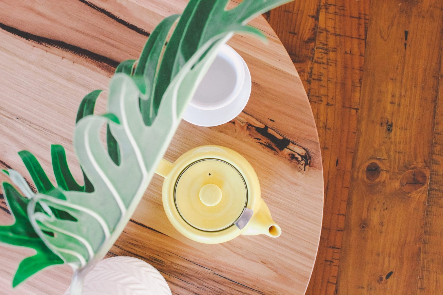 yellow teapot on table near plant